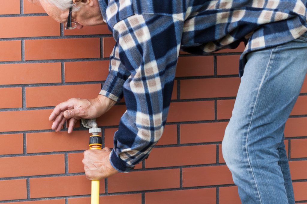 Man winterizing an outdoor spigot