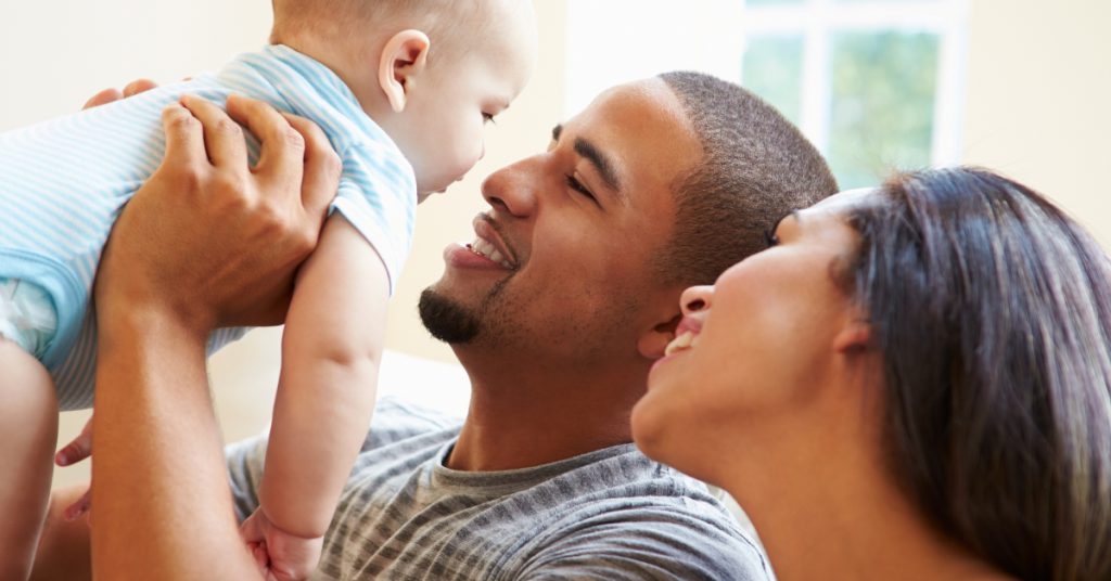 Closeup of parents smiling and holding up their baby