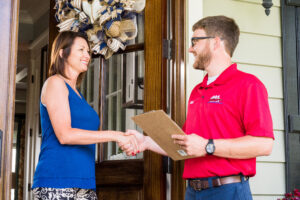 Plumber speaking to a homeowner at their front door. Shaking hands.