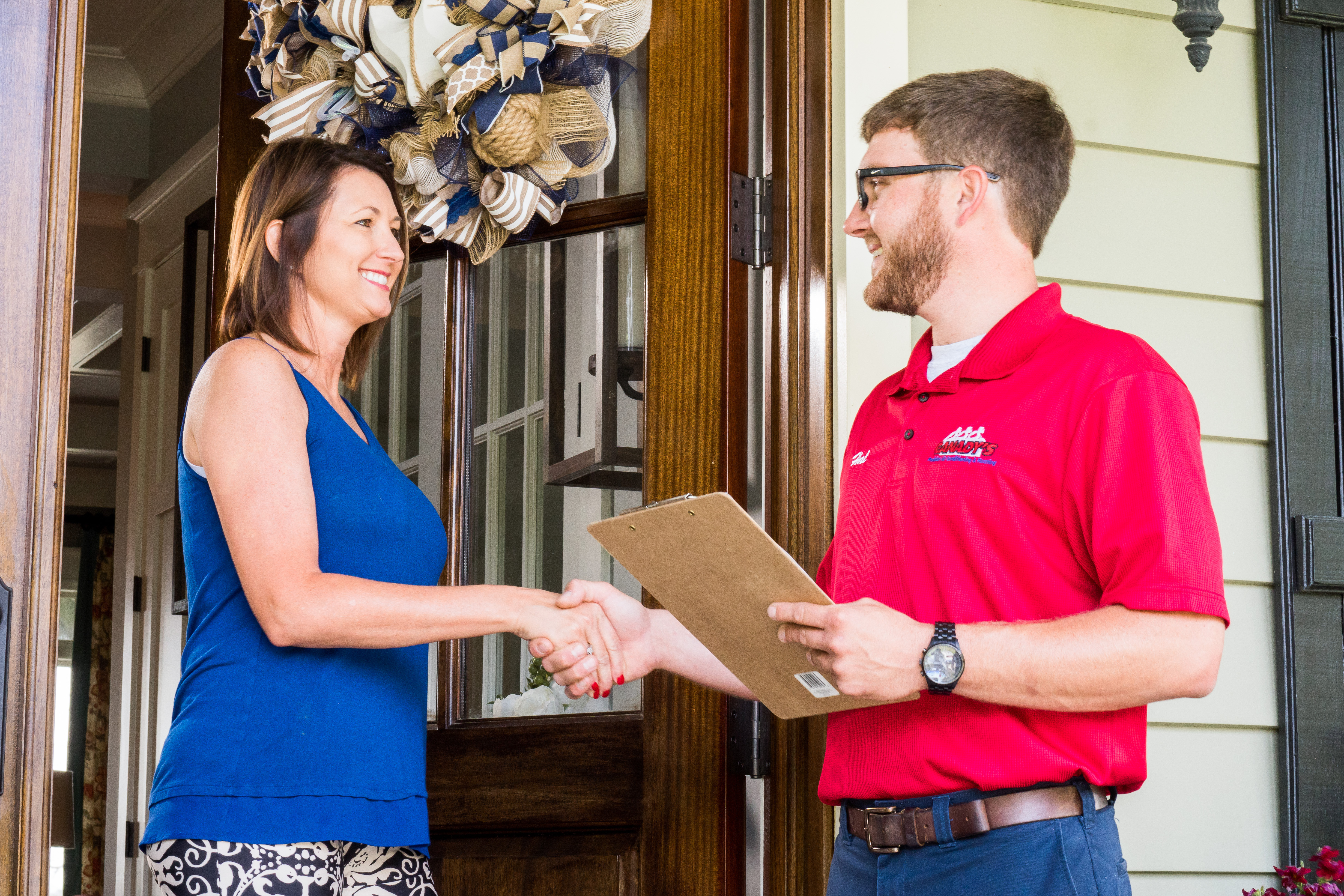 canady's technician smiling and shaking hand of female customer at her front door holding clipboard