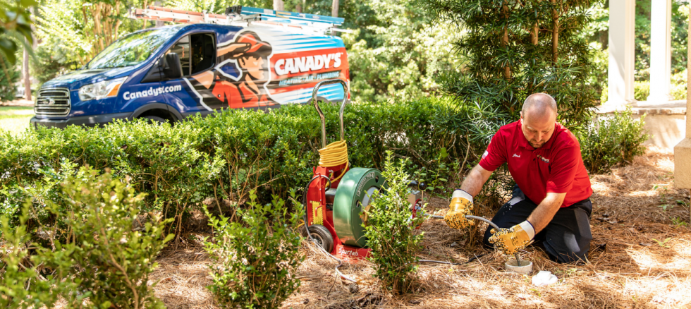 A Candadys plumbing performing a plumbing service outside 